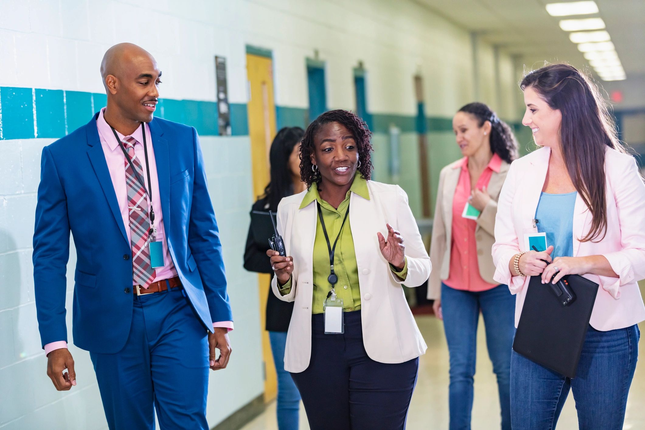 Group of educators walking and talking together in a school hallway