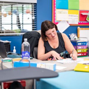 Female teacher in her 40’s at a small private special education school working at her desk indoors