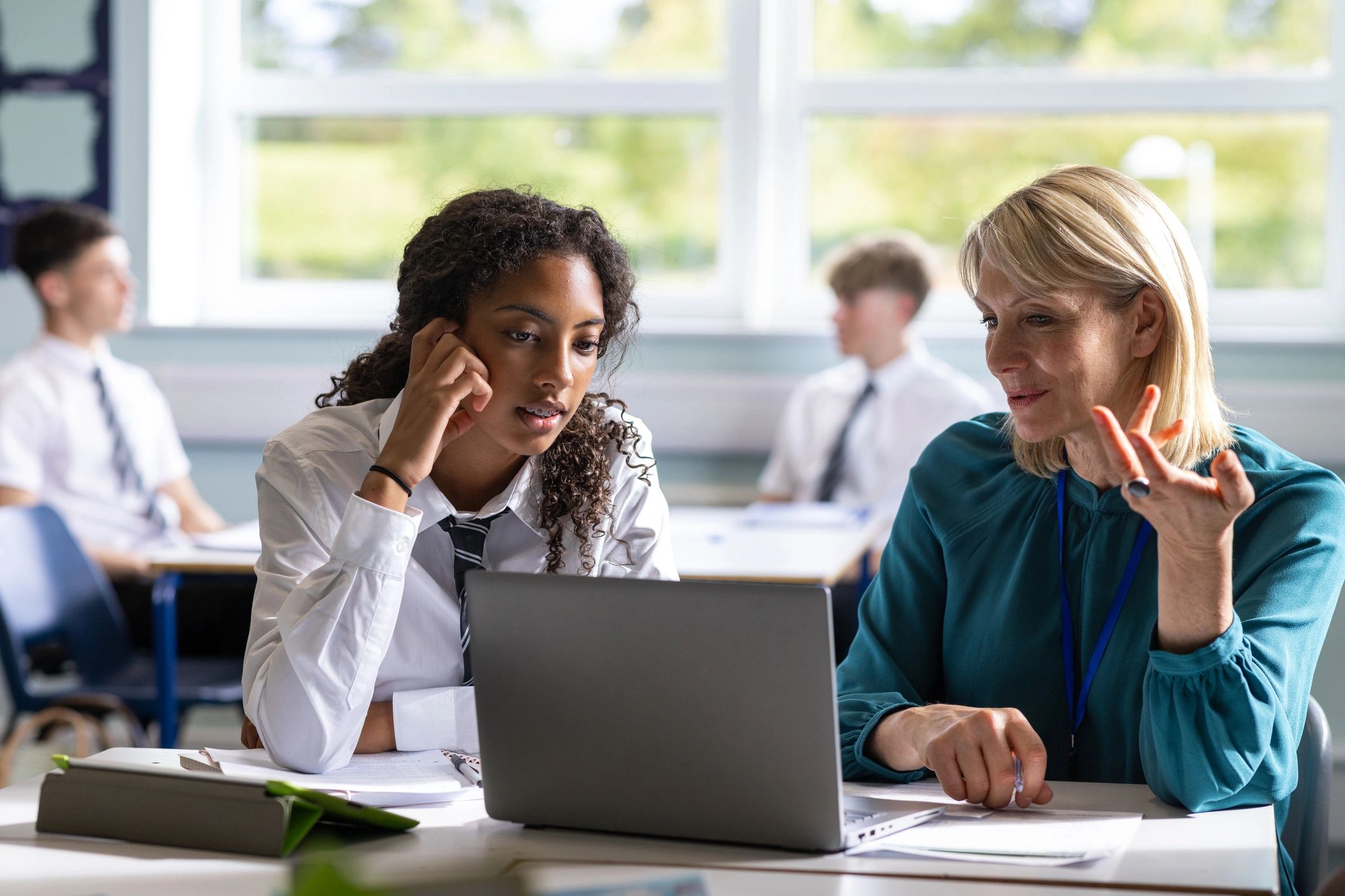 Teacher helping a student with schoolwork in a classroom