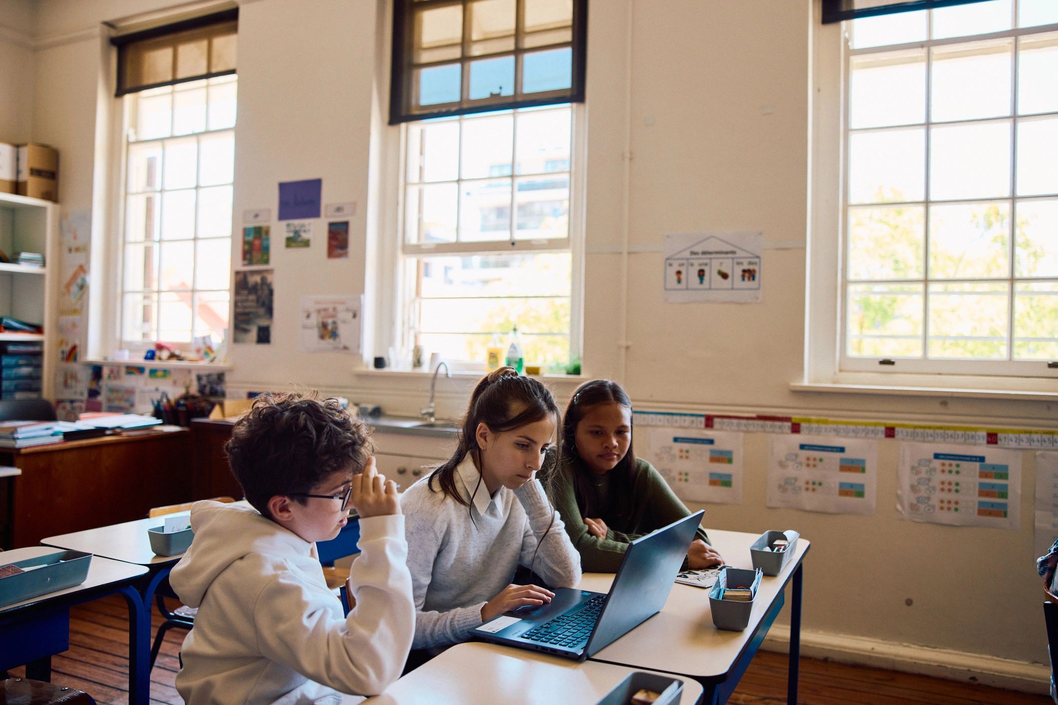 School children using a laptop together in class