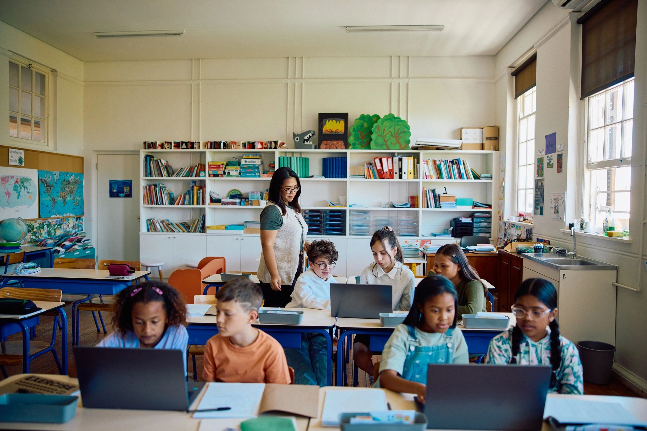 Classroom with teacher guiding learners using laptops
