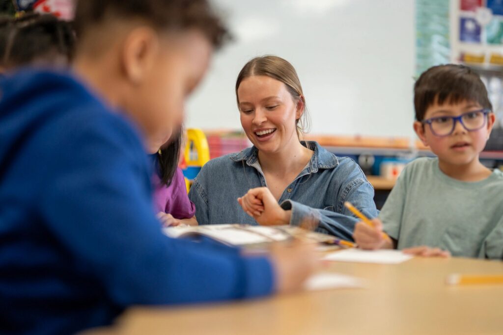 Elementary Teacher Helping Students With Classwork in Bright Inclusive Classroom Setting